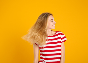 Photo of Portrait of beautiful young woman with blonde hair on yellow background