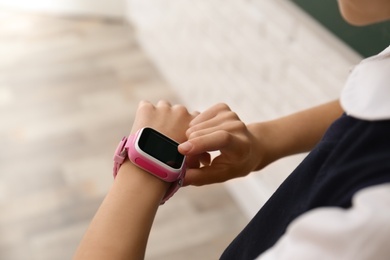 Girl using stylish smart watch in classroom, closeup