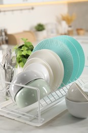 Photo of Many different clean dishware and cutlery on white marble table in kitchen