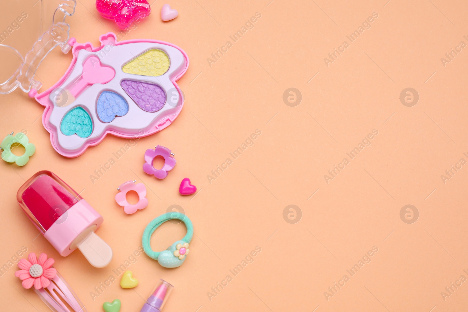 Photo of Children's kit of makeup products and accessories on pale orange background, flat lay. Space for text