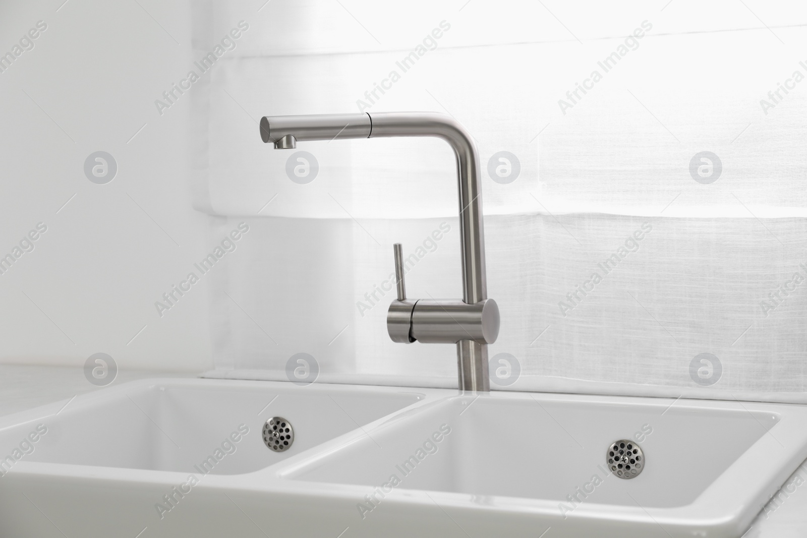 Photo of Modern sink and water tap near window in kitchen. Interior design