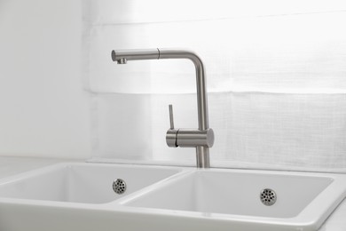 Modern sink and water tap near window in kitchen. Interior design