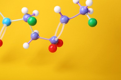 Photo of Structure of molecule on yellow background, closeup and space for text. Chemical model