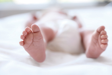 Photo of Newborn baby lying on bed, closeup of legs