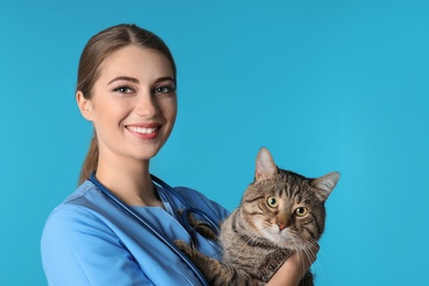 Photo of Veterinarian doc with cat on color background. Space for text