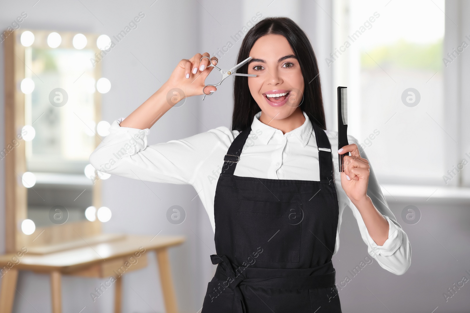 Photo of Portrait of happy hairdresser with professional tools in beauty salon