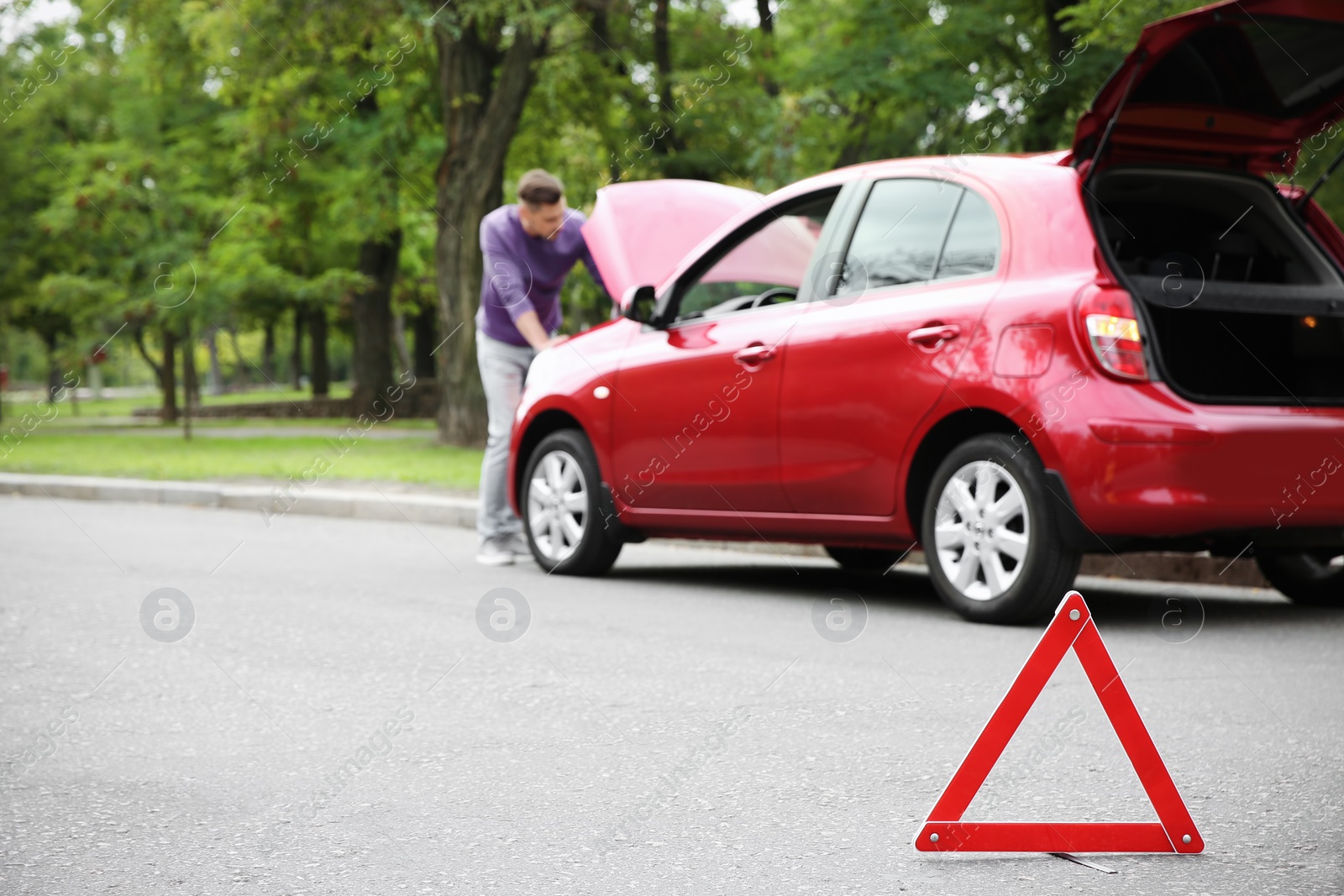 Photo of Emergency stop sign and man near broken car on background