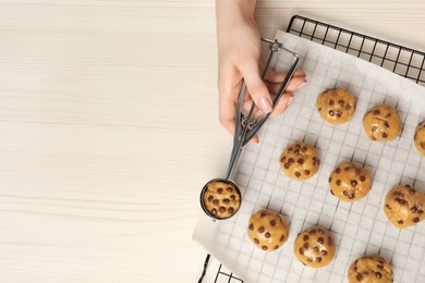 Woman making delicious chocolate chip cookies at white wooden table, top view. Space for text