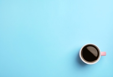 Ceramic cup with hot aromatic coffee on color background, top view