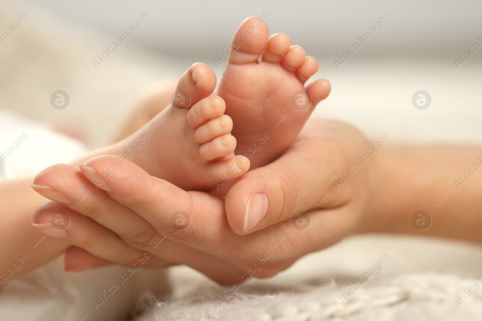 Photo of Mother holding her newborn baby, closeup view on feet. Lovely family