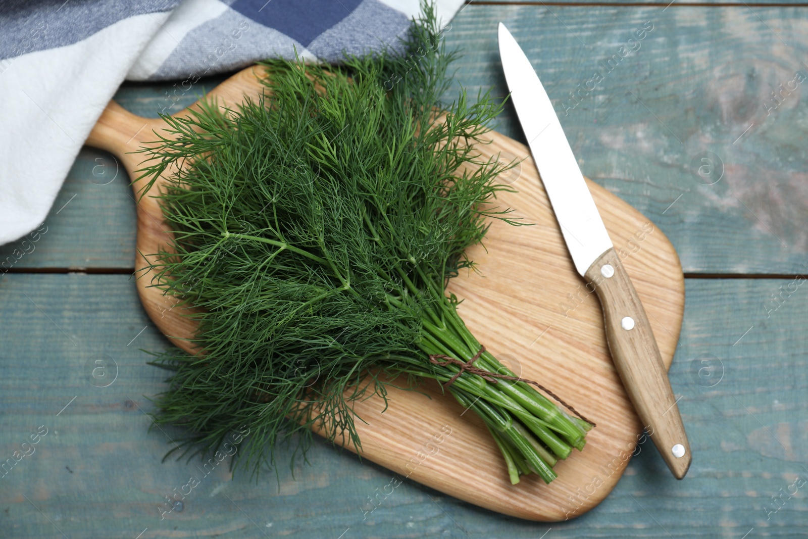 Photo of Bunch of fresh dill on light blue wooden table, flat lay