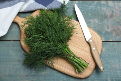 Photo of Bunch of fresh dill on light blue wooden table, flat lay