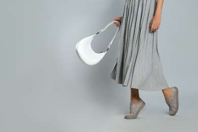 Woman with stylish bag on grey background, closeup. Space for text