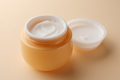 Photo of Jar of face cream on beige background, closeup