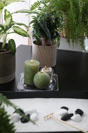 Candles and incense sticks near miniature zen garden on black table