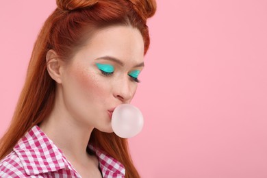 Beautiful woman with bright makeup blowing bubble gum on pink background. Space for text