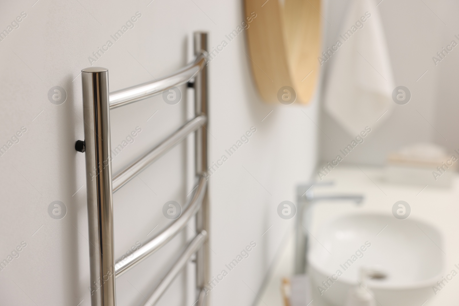 Photo of Heated towel rail on white wall in bathroom, closeup