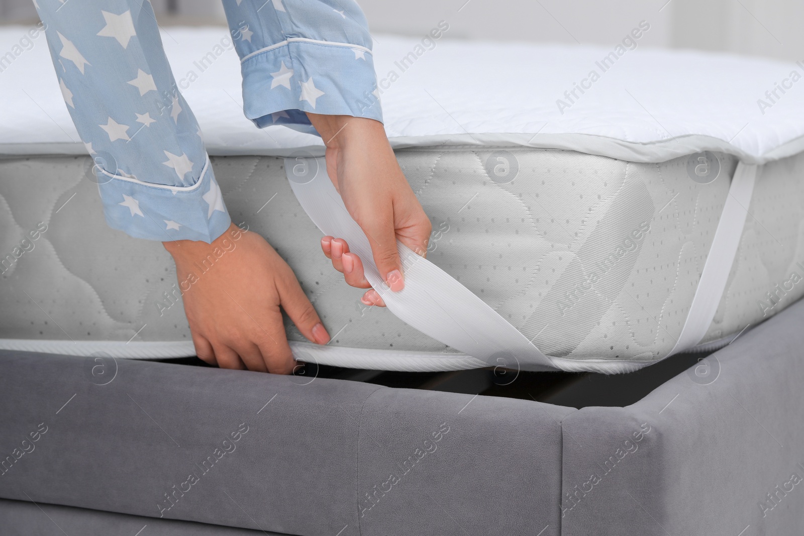 Photo of Woman putting protector on mattress, closeup view