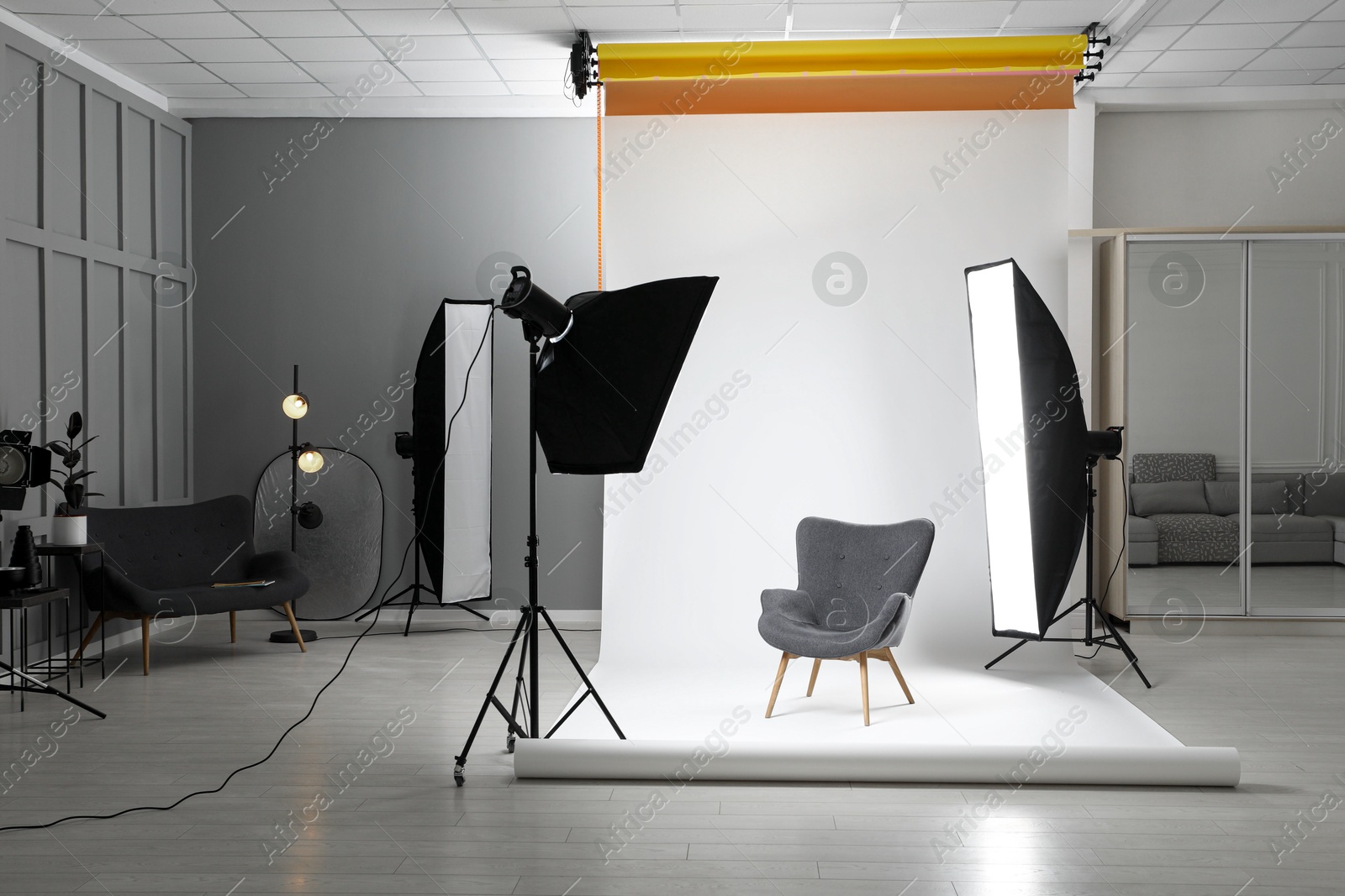 Photo of White photo background, armchair and professional lighting equipment in studio