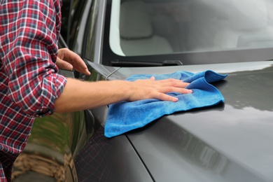 Photo of Man washing car hood with rag, closeup