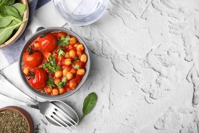 Delicious chickpea curry and seasoning in bowl on white textured background, flat lay. Space for text