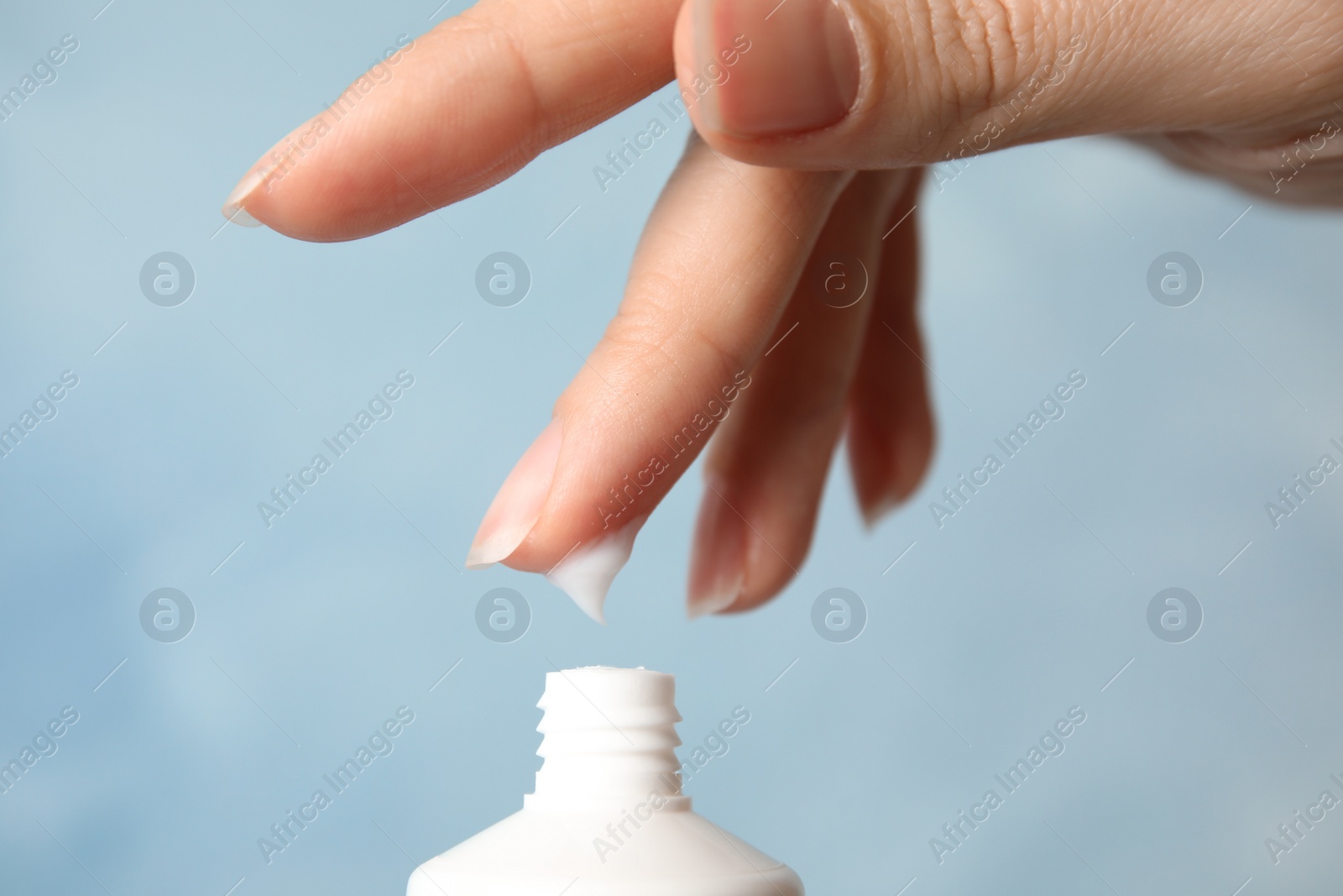 Photo of Woman applying hand cream on color background, closeup