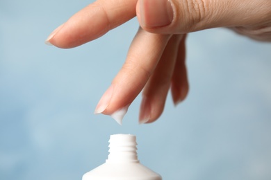 Photo of Woman applying hand cream on color background, closeup