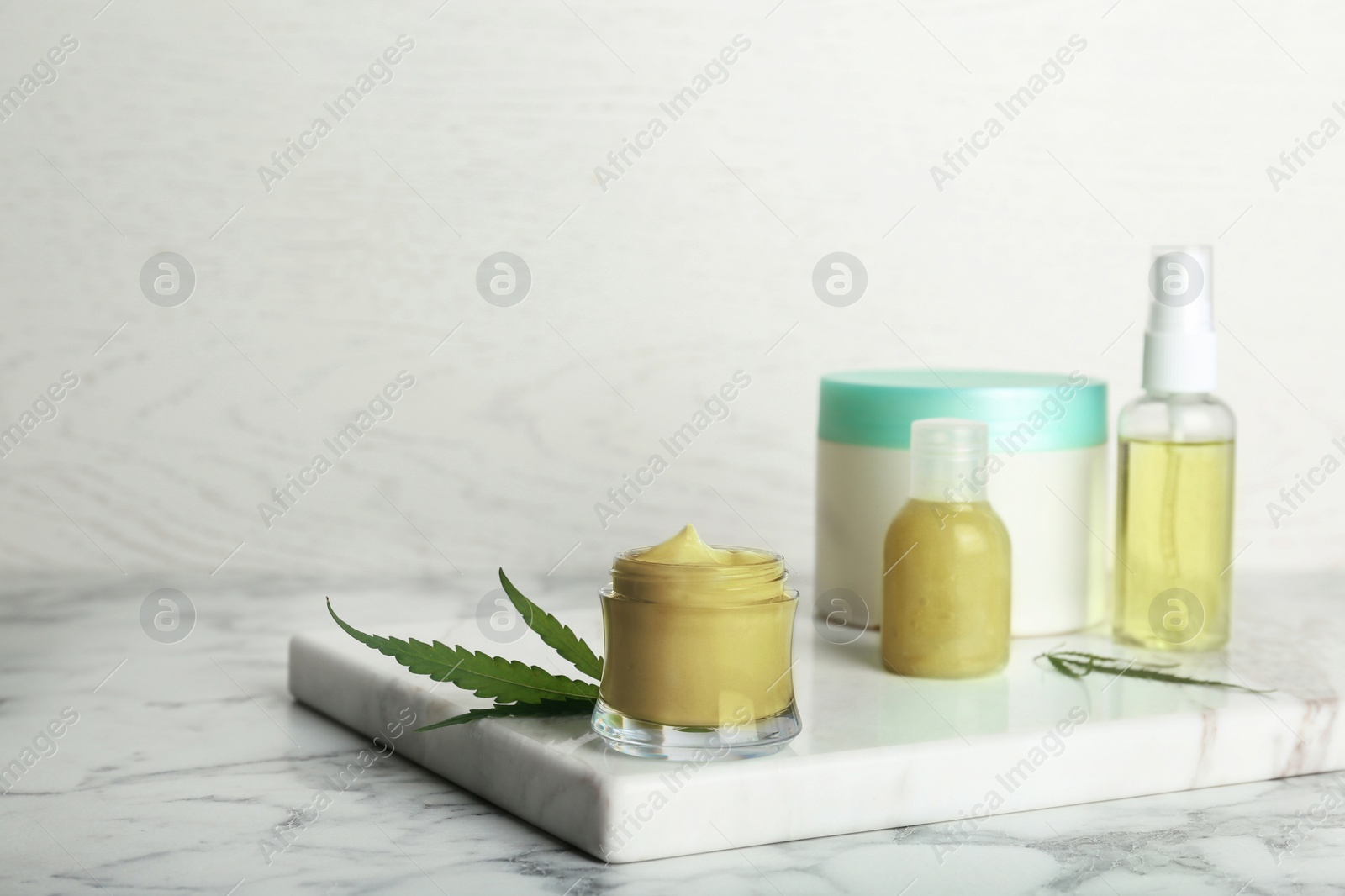 Photo of Composition with hemp lotion on marble table. Space for text