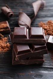 Photo of Pieces of black chocolate on wooden table