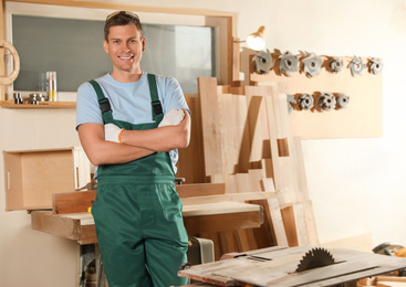 Photo of Professional carpenter in uniform near wooden workbench