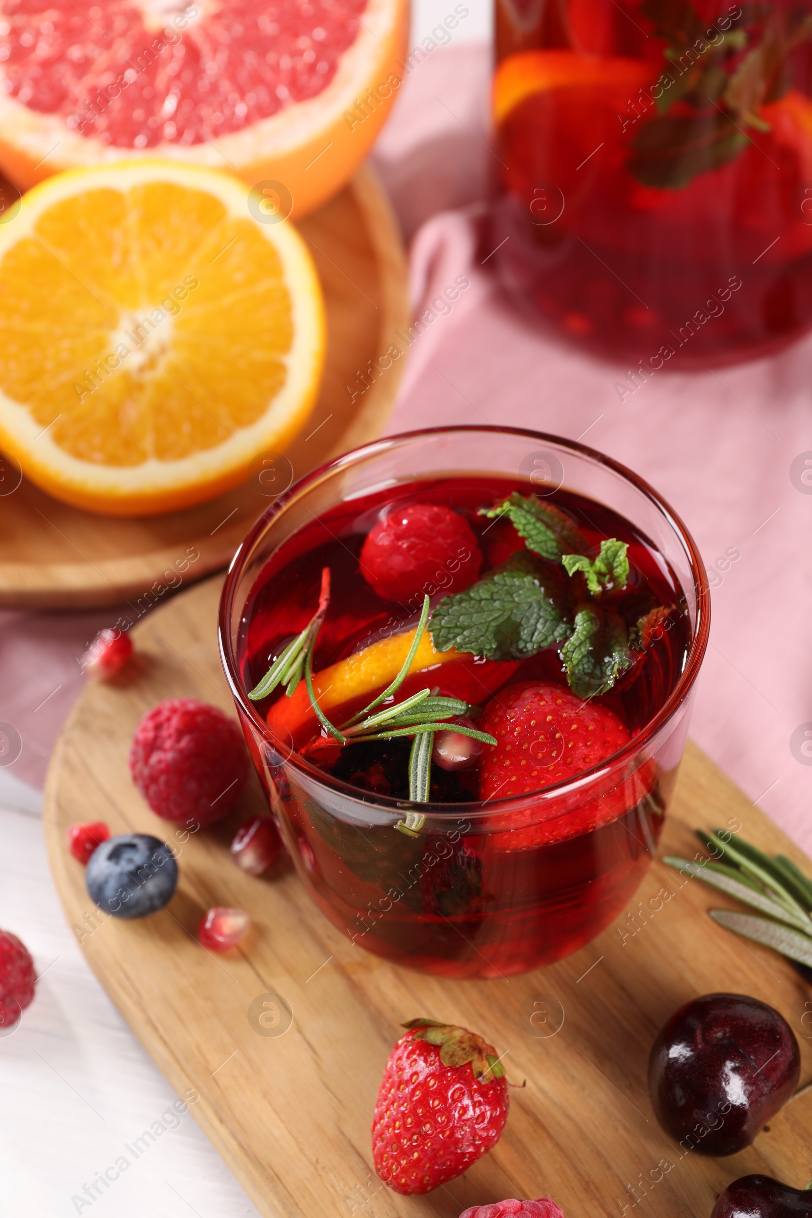 Photo of Glass of delicious sangria, fruits and berries on table