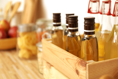 Photo of Bottles of oil on wooden countertop in kitchen, space for text