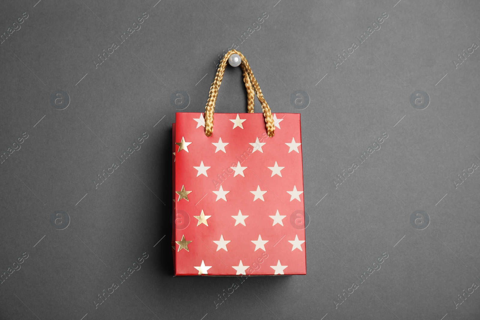 Photo of Red shopping paper bag with star pattern on black background