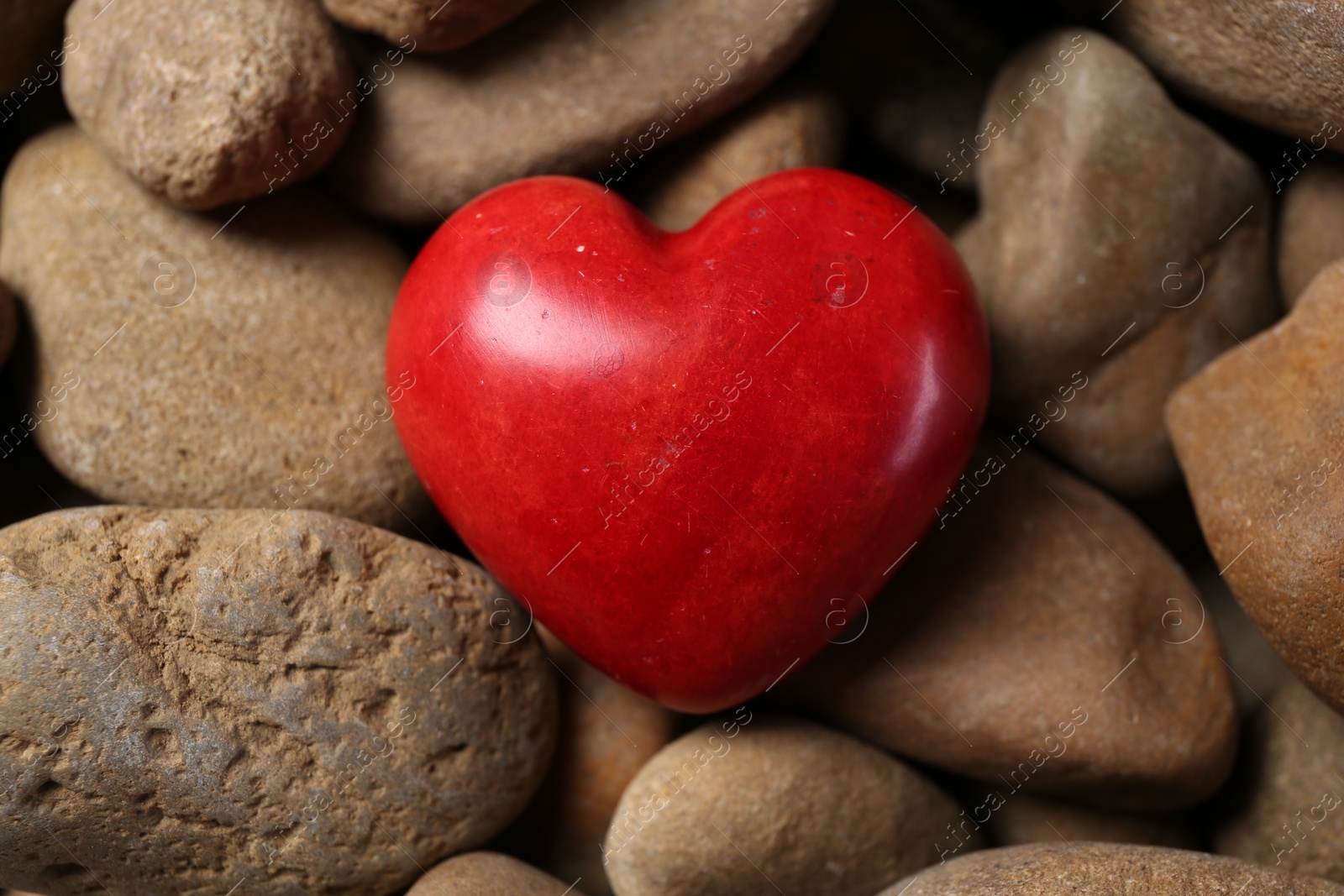 Photo of Red decorative heart on stones, top view