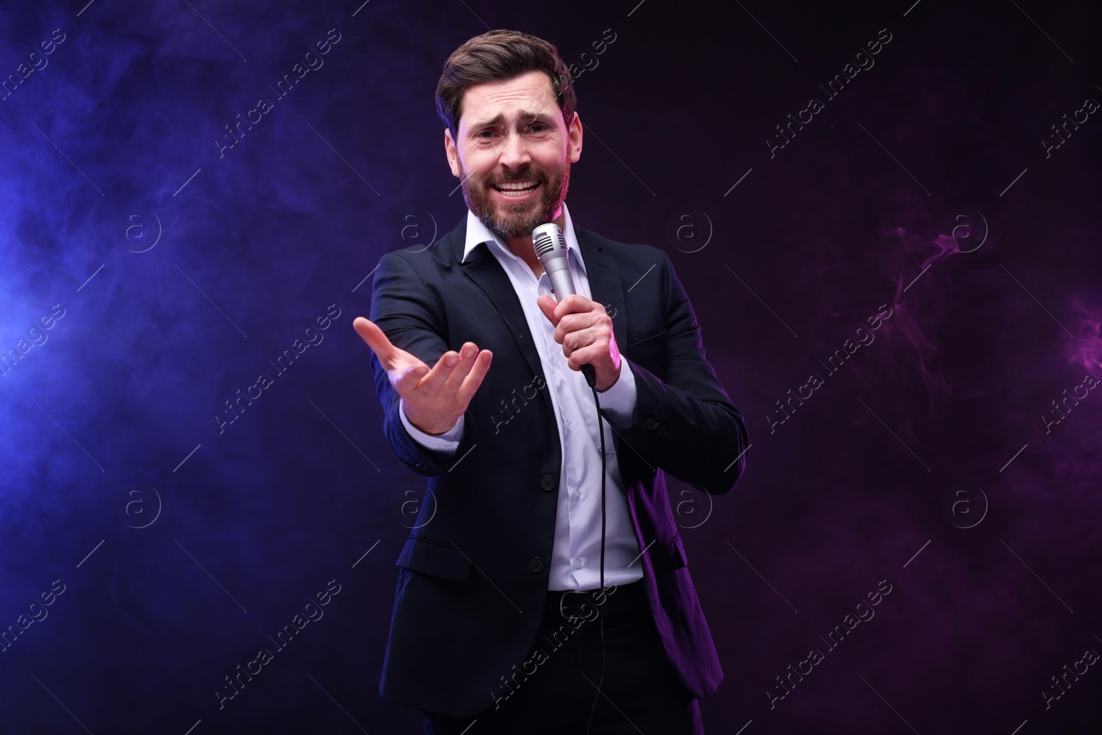 Photo of Emotional man with microphone singing in neon lights