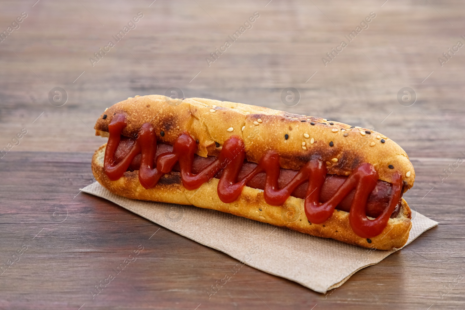 Photo of Fresh tasty hot dog with ketchup on wooden table, closeup