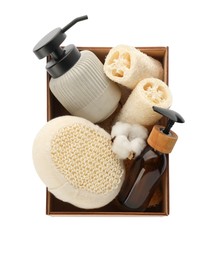 Set of toiletries with natural loofah sponges in wooden crate isolated on white, top view