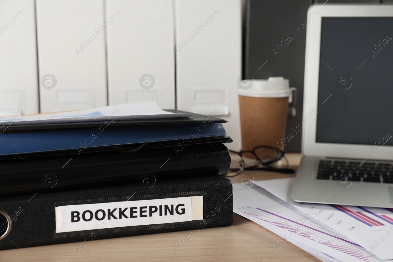 Photo of Folders, laptop and documents on desk in office. Bookkeeper's workplace