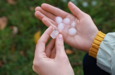 Photo of Woman holding hail grains after thunderstorm outdoors, closeup