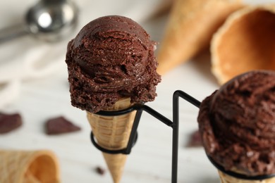 Photo of Chocolate ice cream scoops in wafer cones on stand, closeup