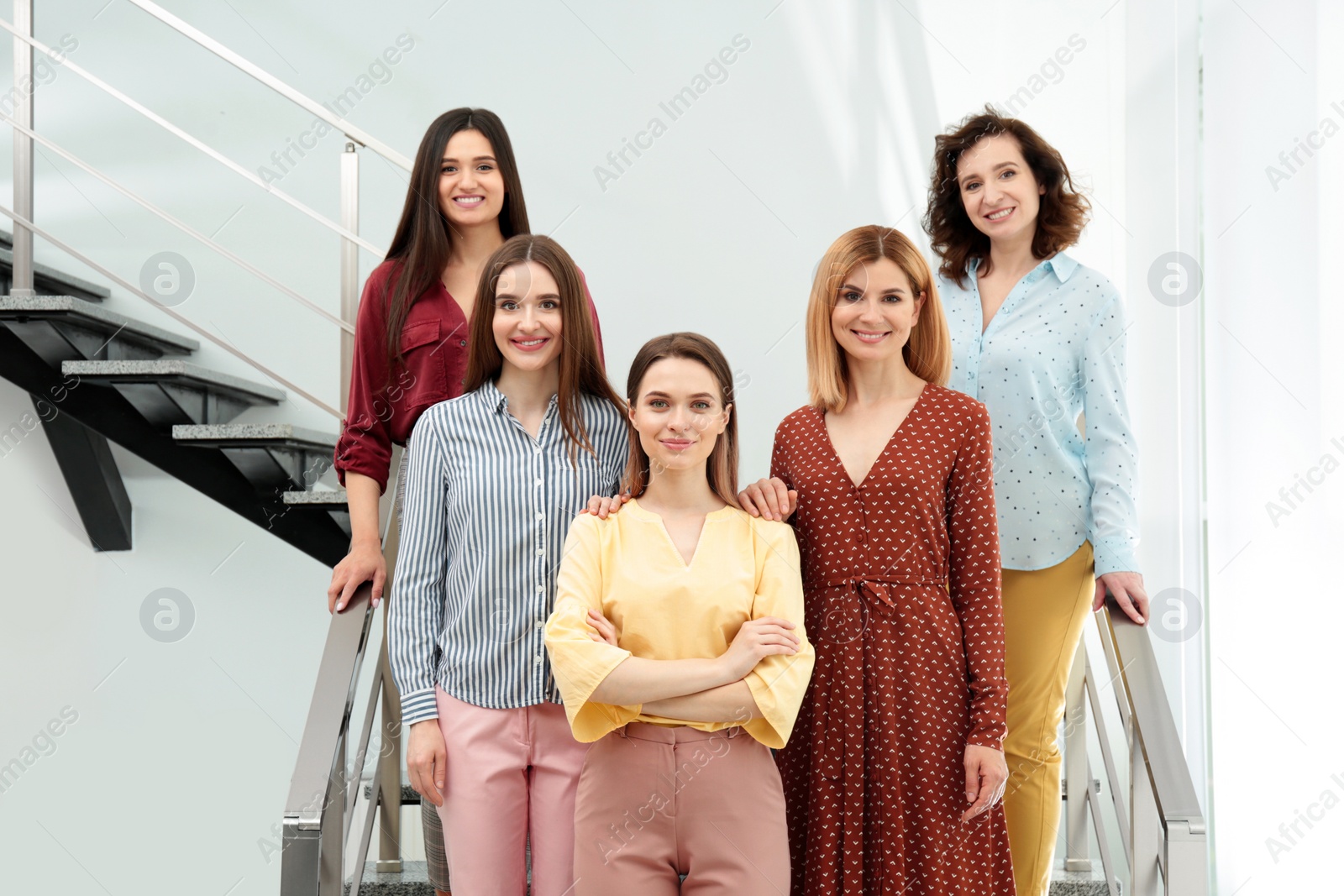 Photo of Portrait of happy ladies on stairs indoors. Women power concept