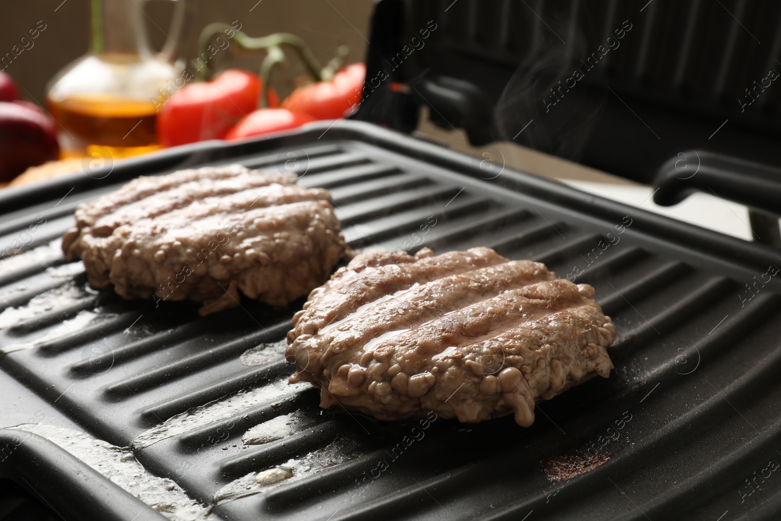 Photo of Delicious hamburger patties cooking on electric grill, closeup