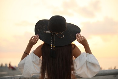 Photo of Young woman in hat at sunset, back view