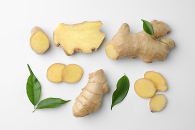 Photo of Fresh ginger with green leaves on white background, flat lay