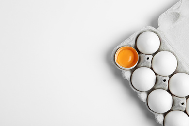 Photo of Fresh chicken eggs in box on white background, top view. Space for text