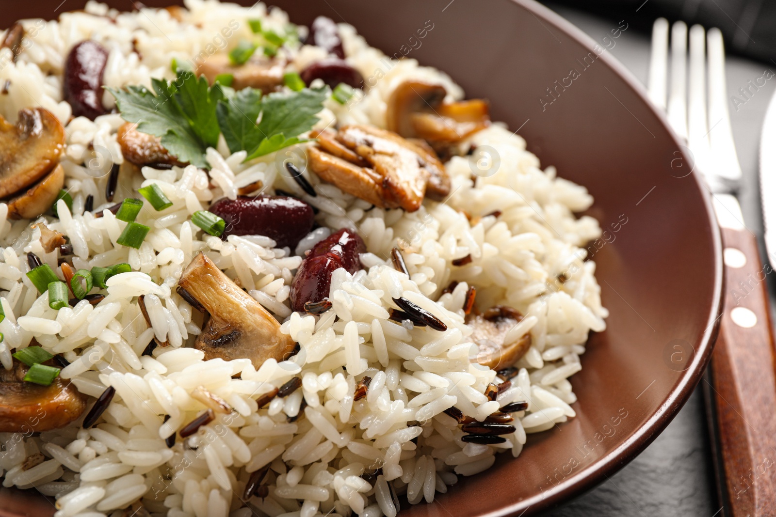 Photo of Delicious rice pilaf with mushrooms and beans in plate, closeup