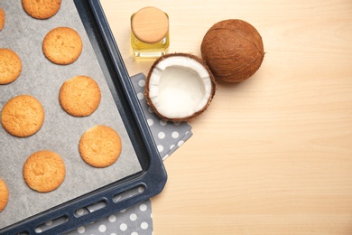 Photo of Baking tray with cookies and coconuts on wooden background