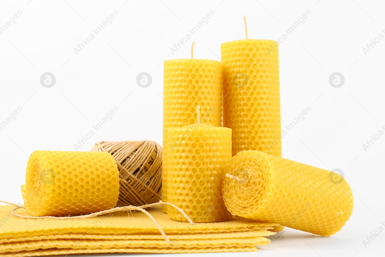 Photo of Stylish elegant beeswax candles, wax sheets and twine on white background