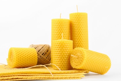 Stylish elegant beeswax candles, wax sheets and twine on white background