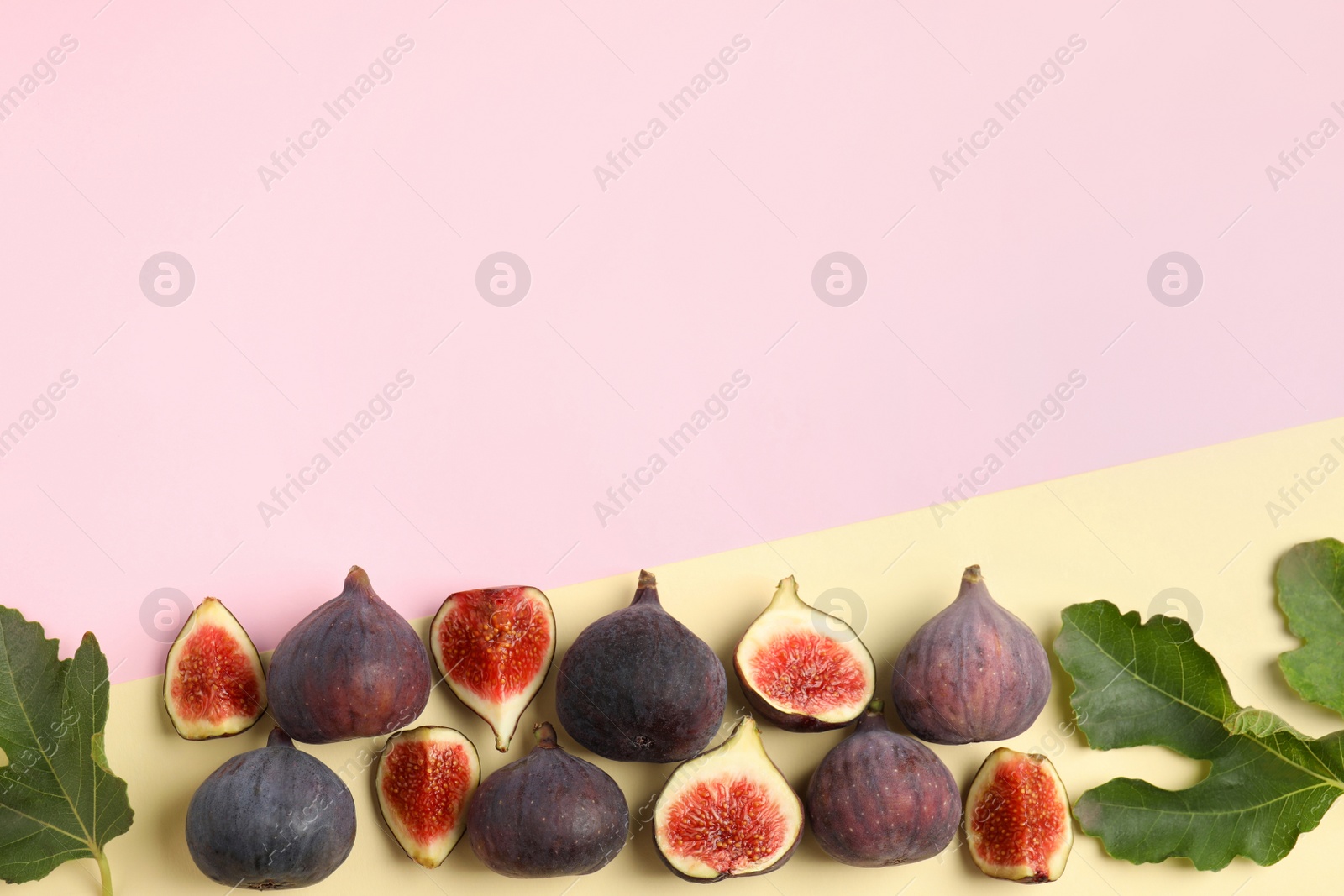 Photo of Delicious ripe figs and green leaves on color background, flat lay. Space for text